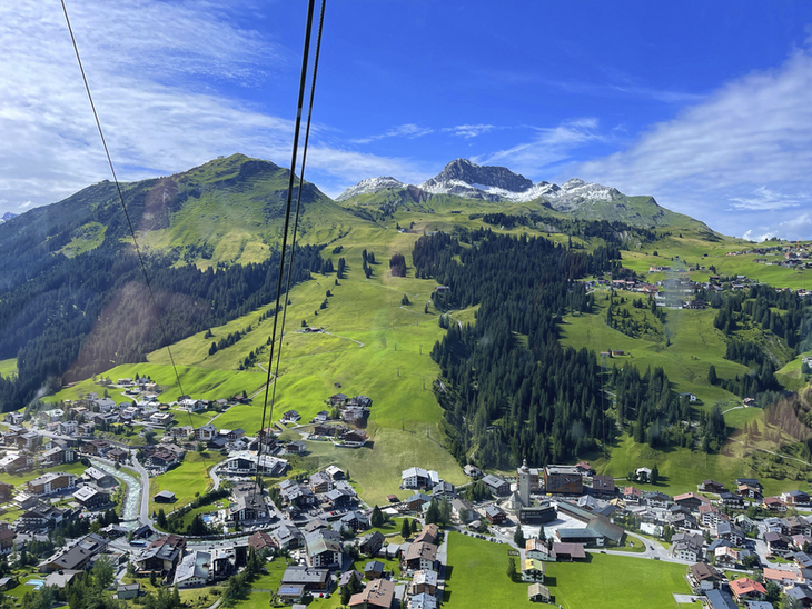 Blick auf Lech am Arlberg und grüne Berglandschaft von der Rüfikopfbahn im Sommer.