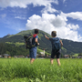 Wanderer mit Rucksäcken schauen auf eine Berglandschaft am Lechweg.