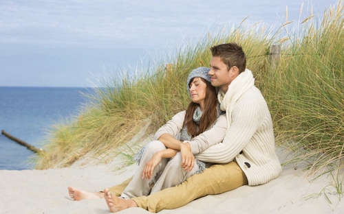 Paar sitzt im Winter am Strand der Nordsee.
