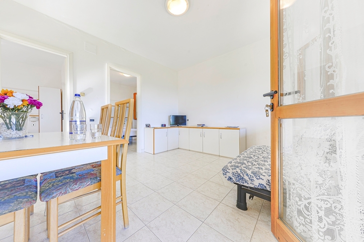 Heller Wohnbereich mit Tisch, Stühlen und TV in einem Bungalow.