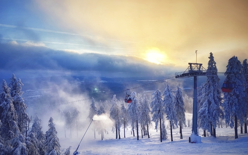 Winterliche Landschaft im Harz mit schneebedeckten Bäumen und Sessellift bei Sonnenuntergang.