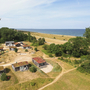 Blick auf ein Stranddorf mit grüner Landschaft und Meer im Hintergrund.