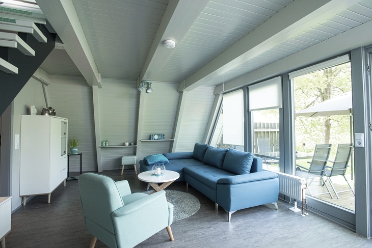 Wohnbereich eines Ferienhauses mit blauer Couch und großem Fenster im Ferienpark Ronshausen.