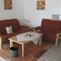 Wohnzimmer mit roten Sofas, Holztisch und Wanddekoration im Ferienpark Ronshausen.