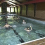 Schwimmbad in einer Halle mit mehreren Menschen beim Schwimmen.