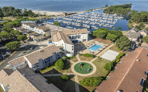 Luftaufnahme einer Ferienanlage mit Pool und Spielplatz am Hafen von Hourtin.