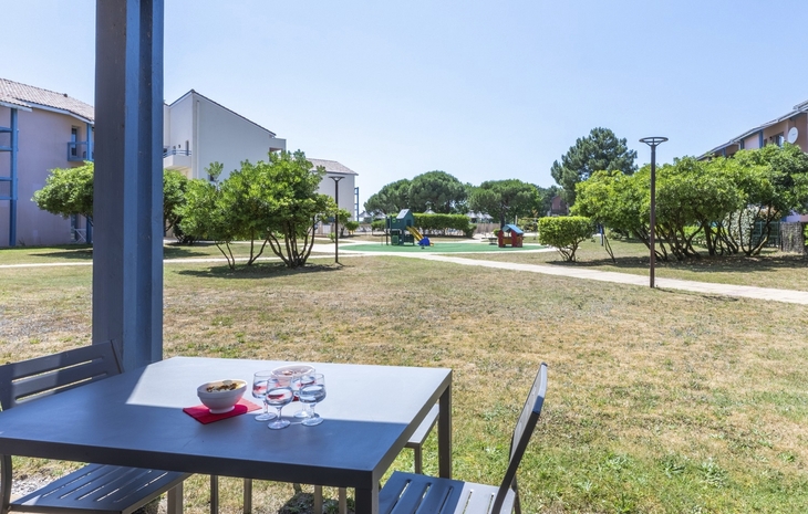 Tisch auf Terrasse mit Blick auf Garten bei der Residenz Odalys du Port.