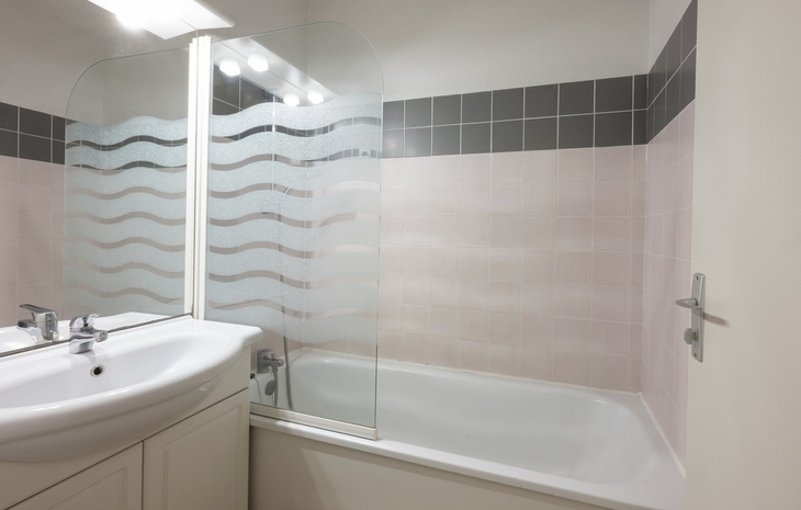 Badezimmer mit weißen Fliesen, Badewanne und Waschbecken.