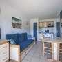 Wohnbereich mit Sofa, Esstisch, Küchenzeile und Wandbild in einem Apartment.