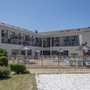 Gebäude mit Pool, Sonnenschirmen und Liegestühlen, blauer Himmel im Hintergrund.