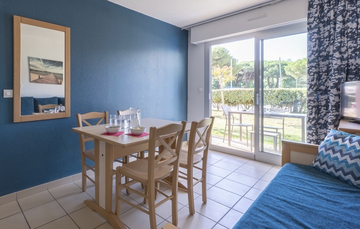 Essbereich mit Holztisch und Stühlen, Blick auf Terrasse und Garten.