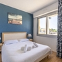 Helles Schlafzimmer mit Doppelbett, Fenster und Wandbild.