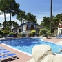 Außenpool mit Sonnenliegen in einem Resort, umgeben von Bäumen und Gebäuden.