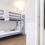 Etagenbett in hell eingerichteten Raum mit Handtüchern und Hut auf Bodenfliesen.