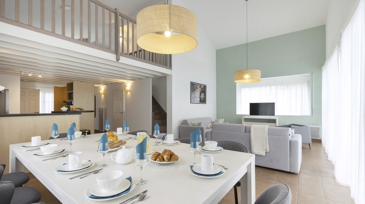 Esszimmer mit gedecktem Tisch und Blick auf Wohnzimmer in moderner Ferienwohnung.