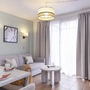 Helles Wohnzimmer mit Sofa, Esstisch, TV und großen Fenstern in einem Ferienapartment.