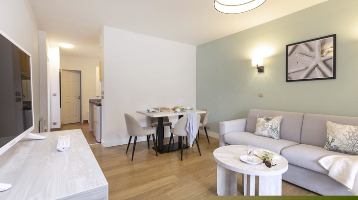 Modernes Wohnzimmer mit Sofa, Esstisch und TV in hellen Farben.