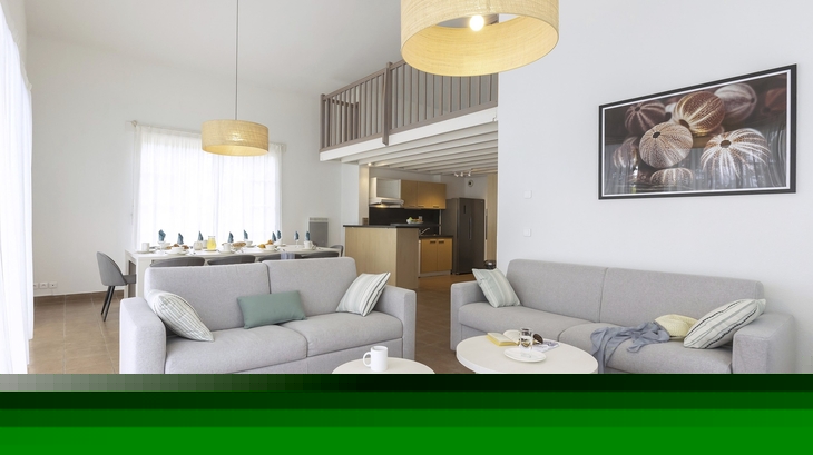 Modern eingerichtetes Wohnzimmer mit Sofas und Esstisch, helle und minimalistische Dekoration.