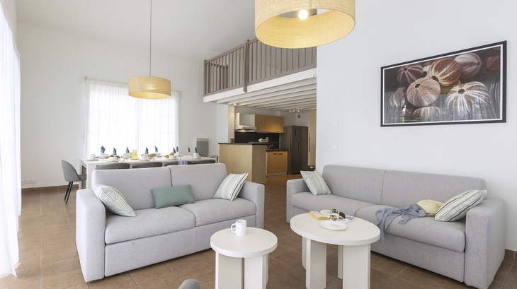 Modern eingerichtetes Wohnzimmer mit Sofas und Esstisch, helle und minimalistische Dekoration.