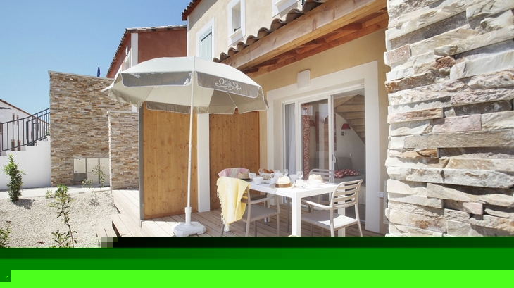Terrasse mit Tisch, Stühlen, Sonnenschirm und Korb vor einem Gebäude.