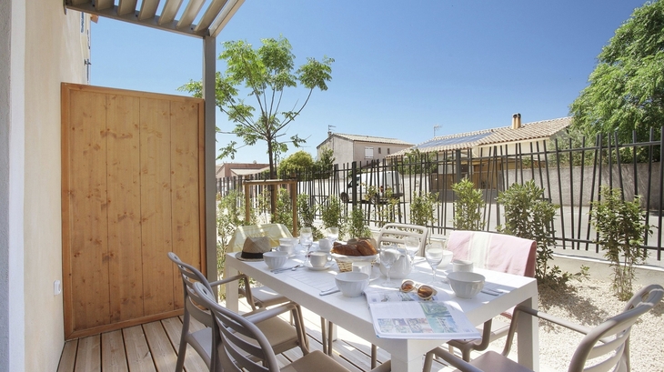 Sonniger Terrassenbereich mit gedecktem Tisch in einer Ferienresidenz.