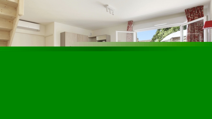 Wohnbereich mit Esstisch, Couch, offener Küche und Zugang zu Terrasse mit Gartenmöbeln.