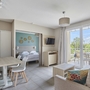 Wohnzimmer einer Ferienwohnung mit Sofa, Esstisch und Blick auf Terrasse und Garten.