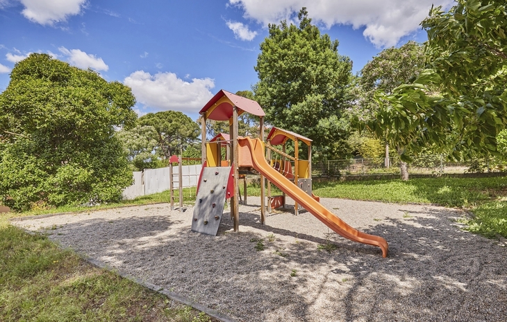 Spielplatz mit Klettergerüst und Rutsche im Freien bei sonnigem Wetter