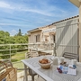 Balkon mit Tisch, Frühstück, Korb, Aussicht auf Grünfläche und Wohnhäuser im Hintergrund.