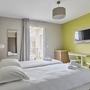 Helles Hotelzimmer mit zwei Einzelbetten, Schreibtisch und Flachbildfernseher.