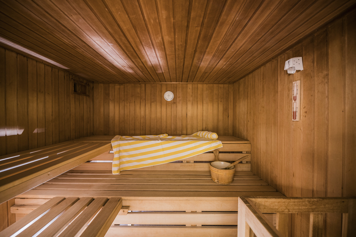 Innenansicht einer Holzsauna mit Handtuch und Saunaeimer.