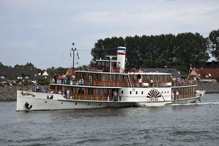 Seitenraddampfer FREYA auf einem Fluss, mit Passagieren an Bord.