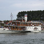 Seitenraddampfer FREYA auf einem Fluss, mit Passagieren an Bord.