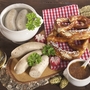 Weißwürste mit Brezen, Senf und Bier auf Holztisch serviert.