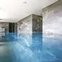 Innenpool im Hotel mit modernen Steinwänden und klarem Wasser.