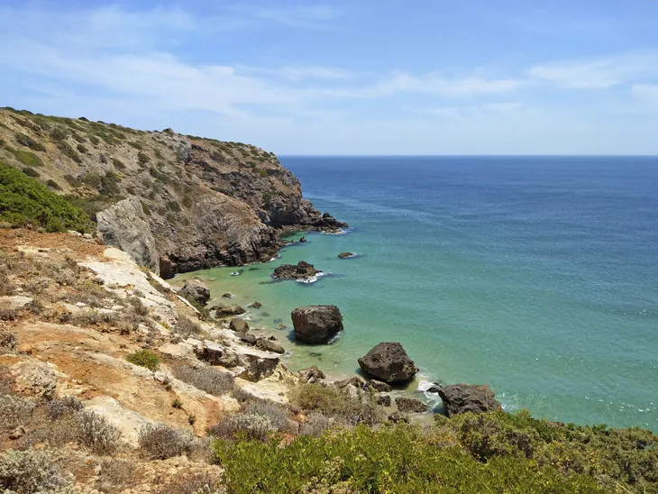 Küste mit Klippen und blauem Meer unter klarem Himmel.
