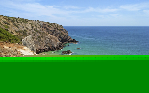 Küste mit Klippen und blauem Meer unter klarem Himmel.