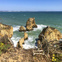 Küste der Algarve in Portugal mit Blick auf Felsen im Meer und blauem Himmel.