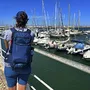 Person mit Rucksack blickt auf einen Hafen mit Segelbooten an der Algarve.