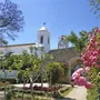 Garten, Blumen und Kirche unter blauem Himmel in Tavira, Algarve.