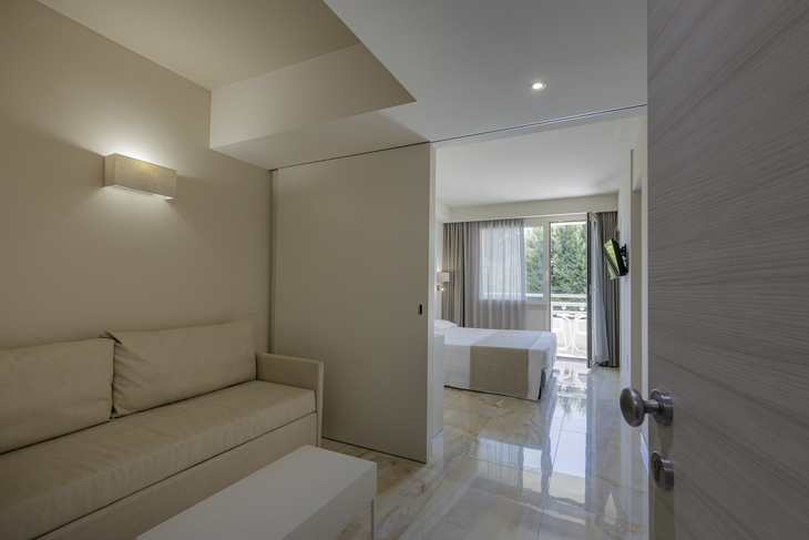 Junior Suite im Hotel mit Sofa, Bett und großem Fenster.