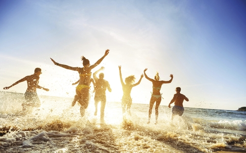 Menschen springen bei Sonnenuntergang ins Meer.