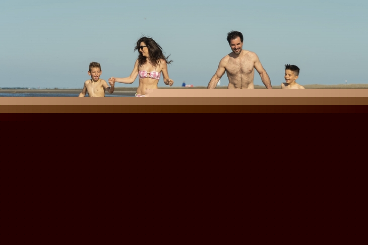Familie läuft am Strand von Albarella im seichten Wasser.