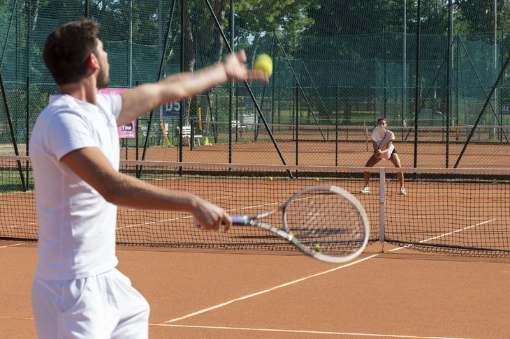 Zwei Personen spielen Tennis auf Sandplatz in Albarella.