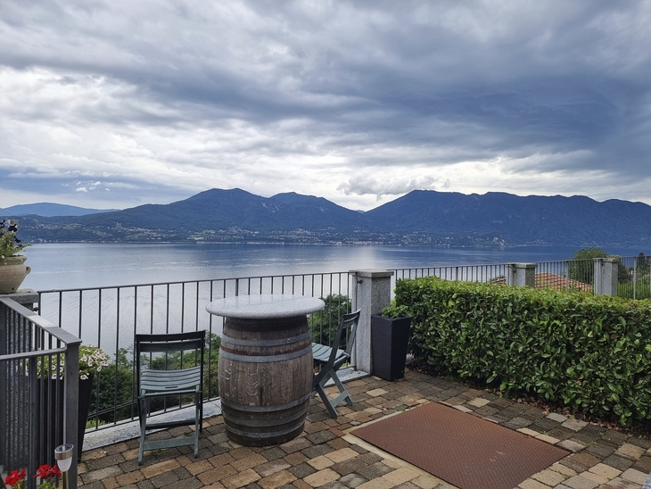 Terrasse mit Tisch und Stühlen, Blick auf See und Berge im Hintergrund
