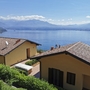 Gelbes Haus mit Terrakottadach, Blick auf See und Berge im Hintergrund.