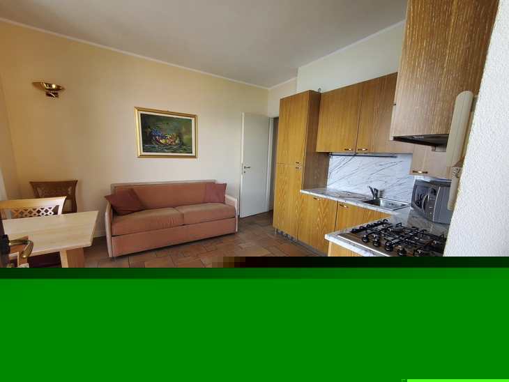 Kleine Küche mit Holzmöbeln, Esstisch und Sofa in einer Ferienwohnung.