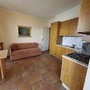 Kleine Küche mit Holzmöbeln, Esstisch und Sofa in einer Ferienwohnung.