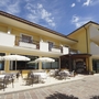 Außenansicht eines gelben Hotels mit Terrasse und Sonnenschirmen.