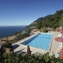 Blick auf einen Pool mit Sonnenschirmen und See im Hintergrund in Tignale.
